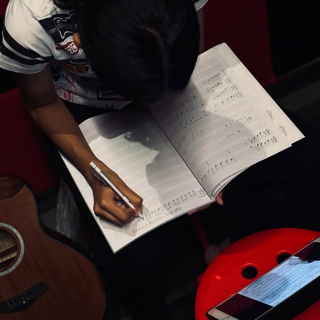 A SARA student writing music notation in a workbook